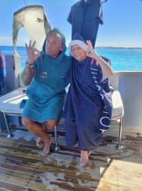 A joyful moment captured on a boat with two individuals posing happily, showcasing the fun and camaraderie of a day on the water.