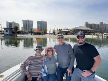 A cheerful group poses together on a boat with a scenic waterfront backdrop, perfect for capturing memories during a fun day on the water.