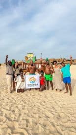 A joyful group poses on the beach with a banner for Sunghada Boat Tours, celebrating their adventure in a picturesque setting.
