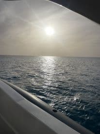 A serene view of the sun setting over calm waters, captured from the deck of a boat — perfect for those seeking tranquility on the water.
