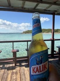 A refreshing Kalik beer is showcased against a stunning Bahamian backdrop, perfect for enjoying a tropical getaway by the water.