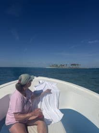 A woman enjoys a refreshing drink while relaxing on a boat, with a picturesque island in the background — a perfect moment for leisure on the water.