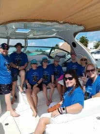 A cheerful group of friends gathers on a boat, celebrating together in matching shirts — perfect for memorable outings and adventures on the water.