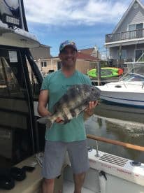 A proud angler displays his impressive catch aboard a boat, showcasing the thrill of fishing adventures on the water.