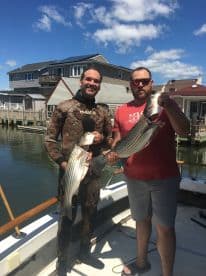Two friends proudly display their catch after a successful fishing trip, showcasing the thrill of fishing adventures on the water.