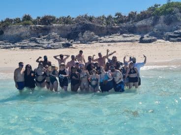 A lively group of friends celebrates at the beach, enjoying the clear waters and sunshine — perfect for memorable summer outings.