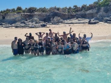 A lively group of friends enjoys a day at the beach, celebrating in the clear waters — perfect for unforgettable summer memories.
