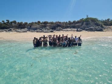 A lively group enjoys a fun day at the beach, celebrating in the clear waters of a tropical paradise — perfect for group outings and memorable experiences.