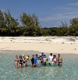A joyful group of family and friends enjoys a fun day at the beach, splashing in the shallow waters — perfect for memorable sandbar stops and family gatherings.