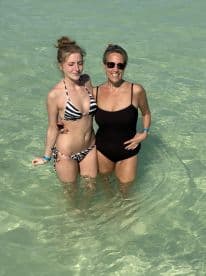 A mother and daughter enjoy a refreshing swim in crystal-clear waters, capturing a joyful moment together in a tropical paradise.
