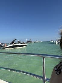 A lively scene of boats enjoying a sunny day on the water, showcasing the vibrant atmosphere of a beach outing with friends.