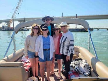 A cheerful group of friends poses on a pontoon boat, enjoying a sunny day on the water — perfect for gatherings and celebrations.