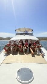 A joyful group of women celebrate together on a boat, each holding beautiful flower bouquets — perfect for a bridal party or special occasion on the water.