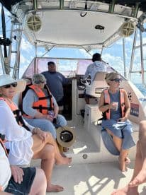 A lively group enjoys their time aboard a boat, showcasing camaraderie and relaxation while sipping drinks in a comfortable interior setting.