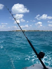 A fishing rod is set up on a boat, ready for an exciting day of fishing in the beautiful turquoise waters.
