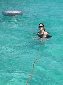 A joyful woman enjoys a refreshing swim in crystal-clear waters, showcasing the perfect day for water activities and relaxation.