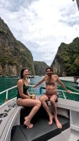 A couple enjoys a scenic boat ride surrounded by stunning cliffs and turquoise waters, perfect for adventure seekers exploring beautiful destinations.