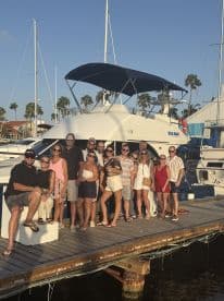 A lively group gathers on the dock in front of the 'Sea Blue' boat, ready for a fun day on the water — perfect for celebrations and group outings.