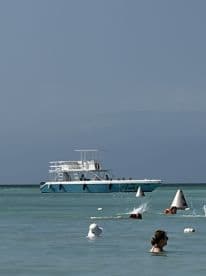A lively scene at the beach with a boat in the background and people enjoying the water — perfect for summer fun and group activities.