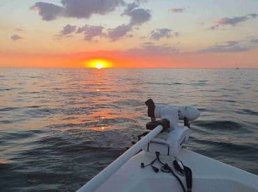 A serene sunset view from the bow of a boat, showcasing the tranquil waters and vibrant colors of the evening sky — perfect for romantic cruises or peaceful getaways.