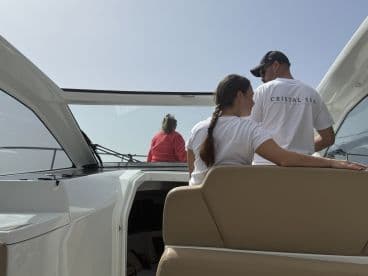 A couple enjoys a moment aboard a boat, with a third person visible in the background, showcasing the relaxed atmosphere of a day on the water.