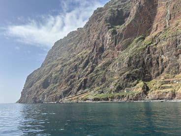 A stunning view of a rugged coastline with lush greenery cascading down the cliffs, perfect for showcasing the natural beauty of the area.