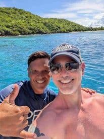 Two friends pose for a cheerful selfie against a stunning ocean backdrop, capturing the joy of their boating adventure.