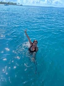 A woman joyfully swims in the crystal-clear ocean, showcasing the fun and excitement of a day on the water.