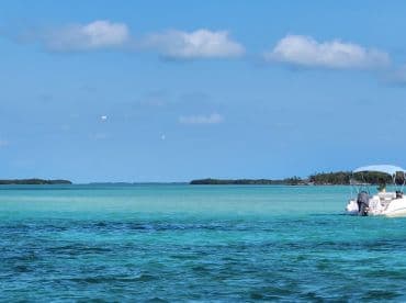 A scenic view of a boat cruising through crystal-clear turquoise waters, surrounded by lush islands — perfect for exploring the beauty of the coastline.