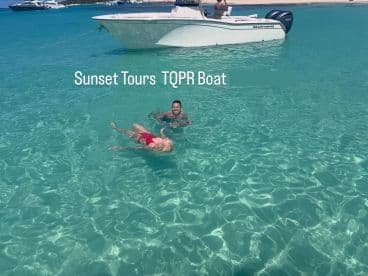 A couple enjoys a refreshing swim in crystal-clear waters near the Sunset Tours TQPR Boat, perfect for memorable aquatic adventures.