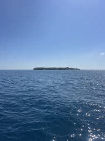 A stunning view of a secluded island surrounded by crystal-clear waters, perfect for exploring or relaxing on a boat trip.