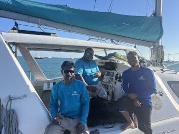 Three crew members relax aboard a sailing vessel, showcasing the camaraderie and expertise that enhance the sailing experience.