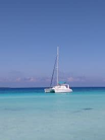 A serene view of a catamaran anchored in crystal-clear turquoise waters, perfect for a relaxing day on the sea.