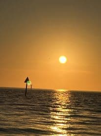A stunning sunset over the ocean, with shimmering reflections on the water, creating a picturesque scene perfect for romantic evenings or peaceful getaways.