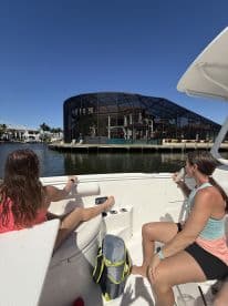 Two friends enjoy a relaxing moment on a boat, taking in the scenic waterfront views — perfect for a day out on the water.