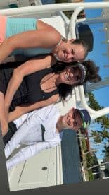 A joyful group of three, including a child, poses for a photo on a boat, capturing a fun moment on the water.