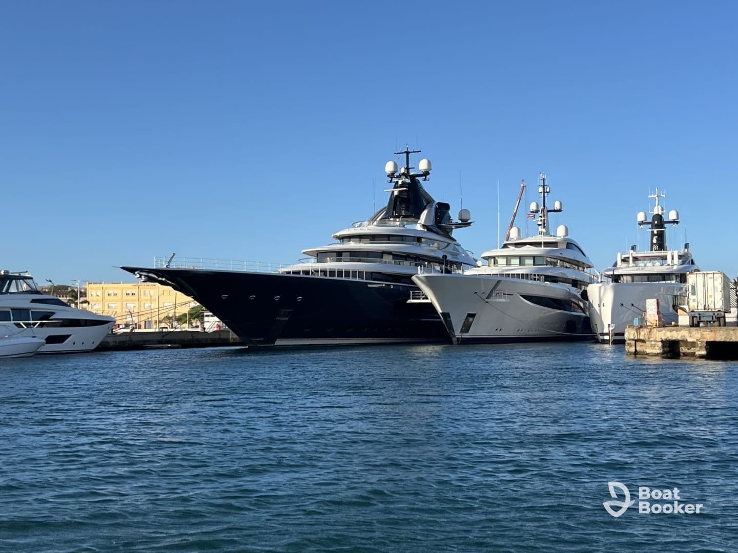 A stunning view of luxury yachts docked at the marina, showcasing their impressive designs against a clear blue sky.