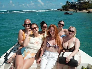 A joyful group of friends poses on a boat under the sun, enjoying their time on the water — perfect for a fun day out with friends.