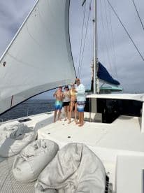 A cheerful group poses on the deck of a catamaran while sailing, capturing a fun moment on the water — perfect for memorable sailing adventures.