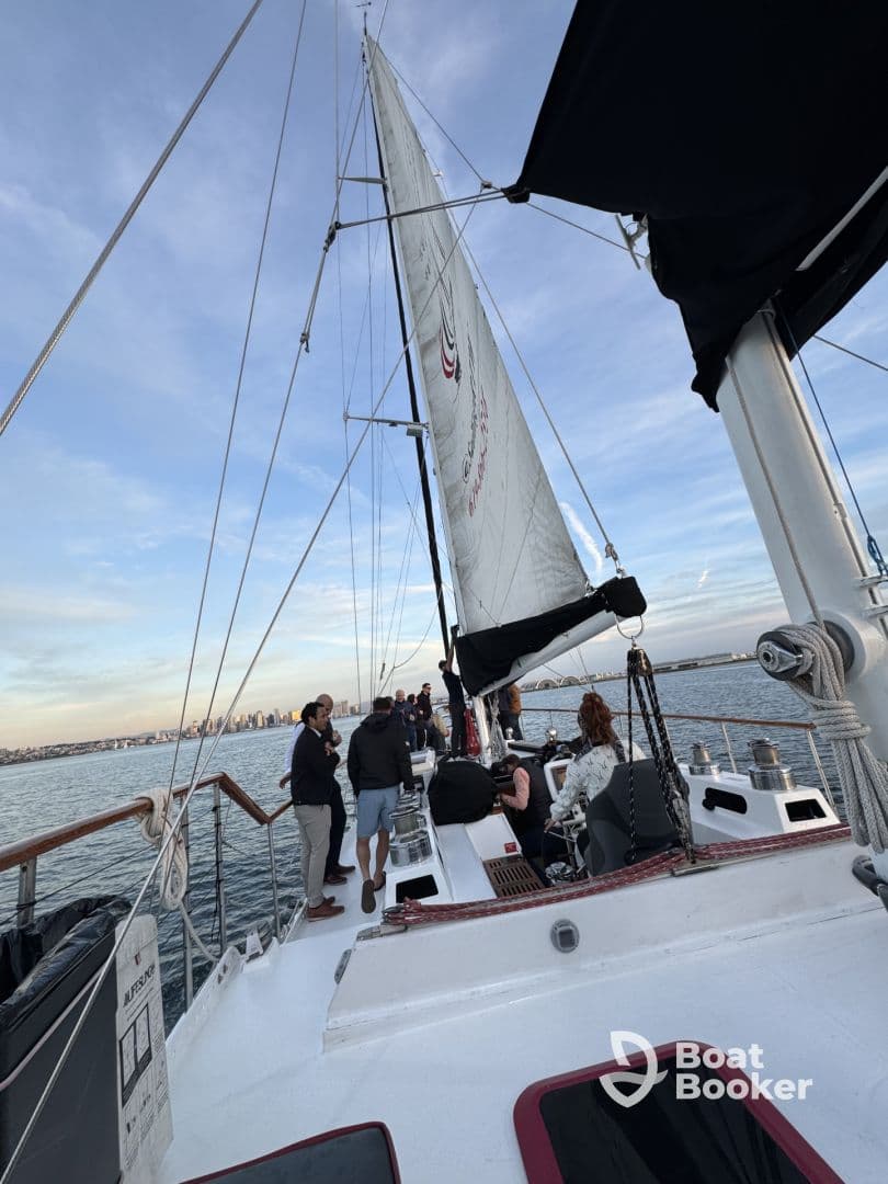 A lively group enjoys a sailing experience on a yacht, with a stunning city skyline in the background — perfect for social gatherings and scenic adventures on the water.