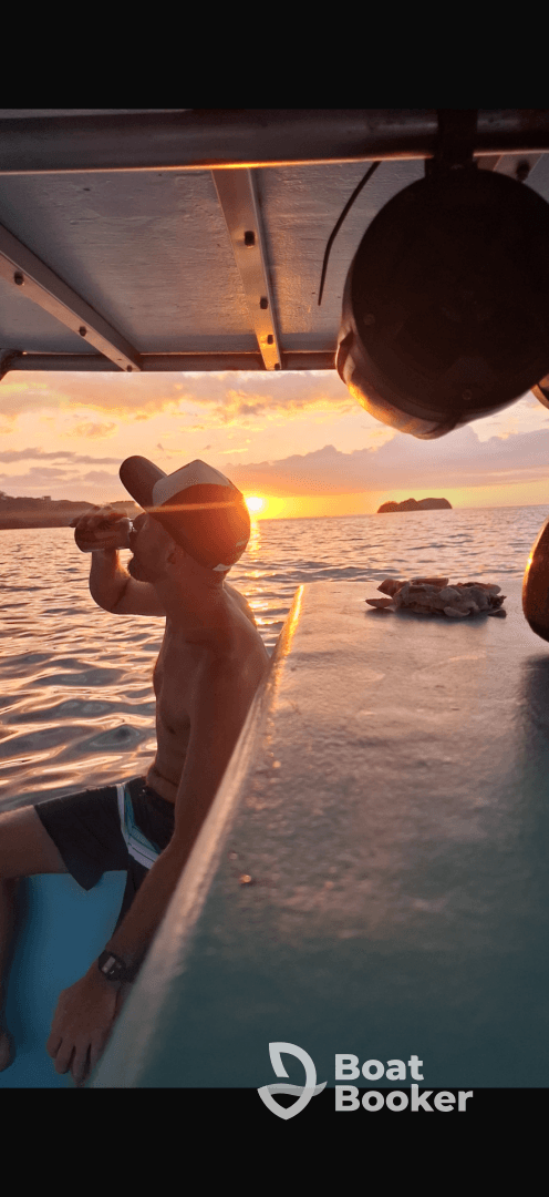 A man enjoys a drink while watching a stunning sunset from a boat, capturing the essence of relaxation on the water.