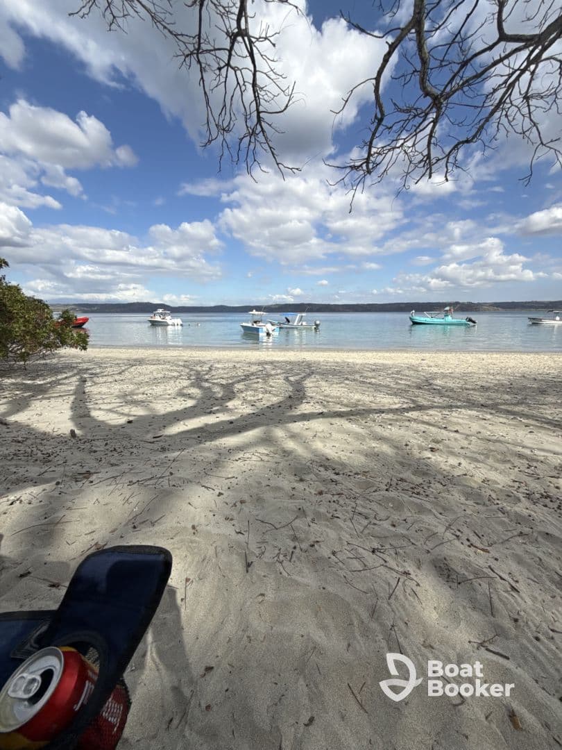 A serene beach scene featuring several boats anchored in calm waters under a beautiful sky, perfect for a relaxing day by the shore.