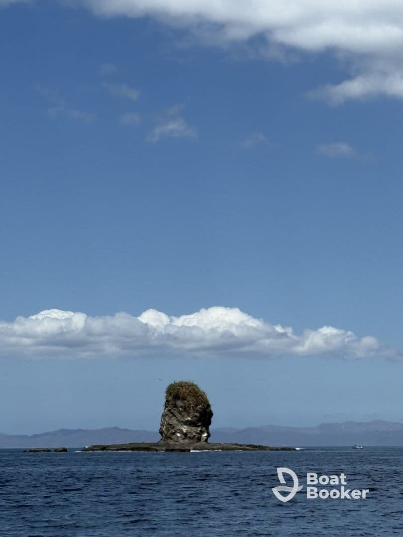 A stunning view of a rocky island surrounded by tranquil waters and a clear blue sky, perfect for showcasing the natural beauty of coastal destinations.