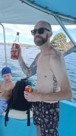 A man raises a bottle while enjoying a day on the water with a child, capturing the essence of fun and relaxation during a boating adventure.
