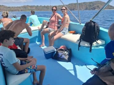 A group of guests relaxes inside a boat's cabin, enjoying the scenic views while seated comfortably. Perfect for family outings or group adventures on the water.