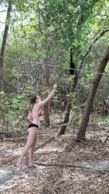 A young woman interacts with a monkey in a lush forest setting, showcasing a unique wildlife encounter that highlights the beauty of nature.