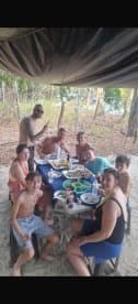 A joyful group enjoys a meal together on the beach, surrounded by nature — perfect for family gatherings and celebrations.