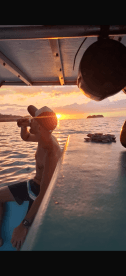 A man enjoys a drink while watching a stunning sunset from a boat, capturing the essence of relaxation on the water.
