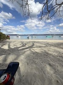 A serene beach scene featuring several boats anchored in calm waters under a beautiful sky, perfect for a relaxing day by the shore.