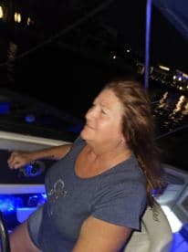 A woman enjoys a night ride on a boat, showcasing the excitement of evening boating adventures.